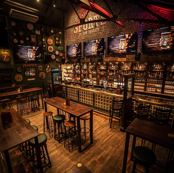 Pub de sport aux briques apparentes, bar en laiton et écrans de match