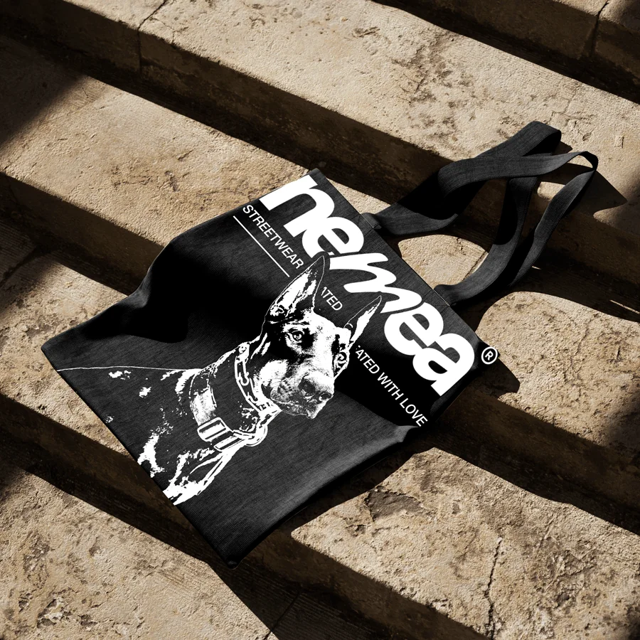 Tote bag Nemea imprimé d'un portrait de doberman, posé sur des marches en pierre
