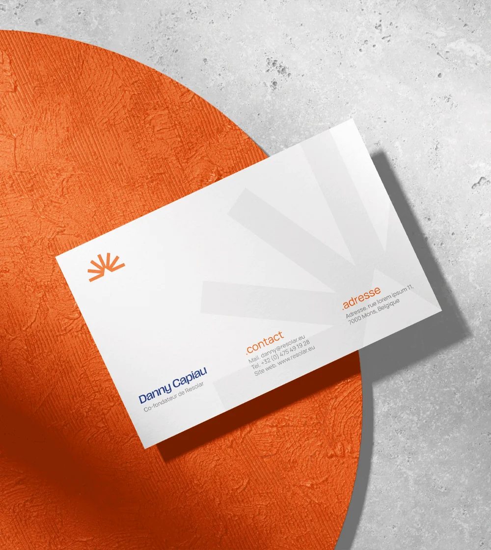 Carte de visite Resolar au nom d'un co-fondateur, posée sur un disque orange texturé, avec le symbole en rayons en grand en filigrane
