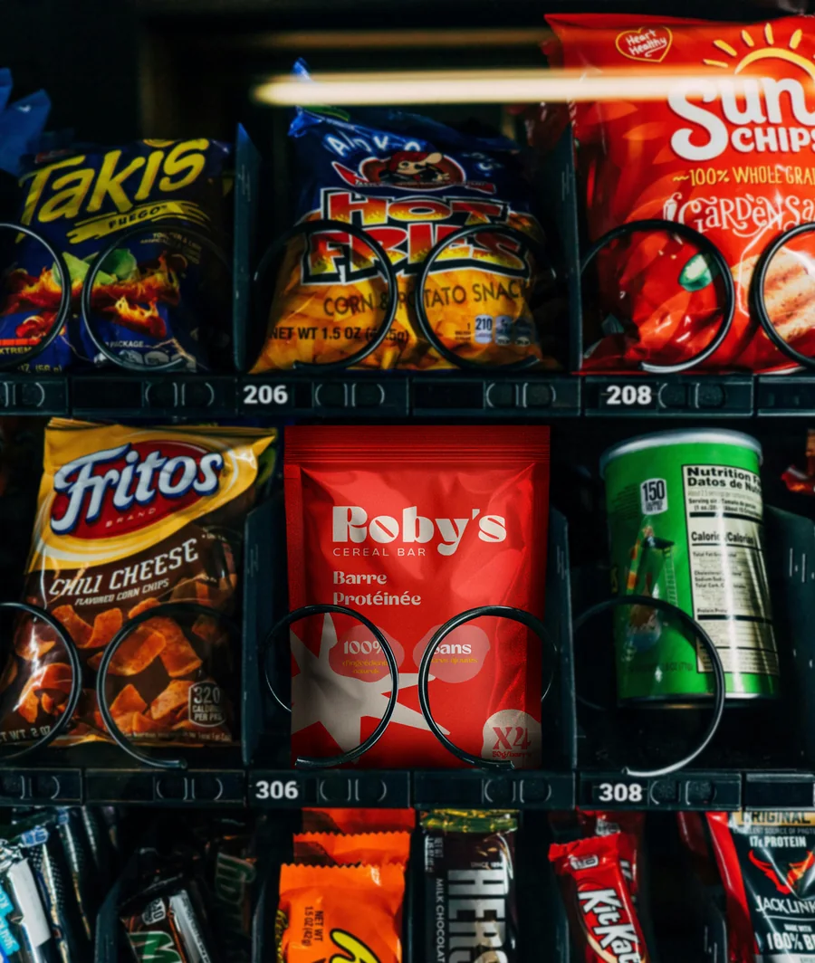 Doypack Roby's Bar rouge dans un distributeur automatique, entre des paquets de chips